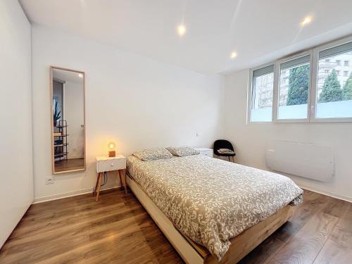 a white bedroom with a bed and a mirror at HYPERCENTRE, agréable T2 style LOFT , FIBRE in Grenoble