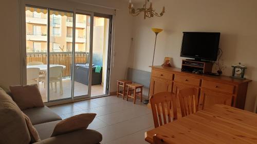un salon avec un canapé, une télévision et une table dans l'établissement appartement frejus plage, à Fréjus