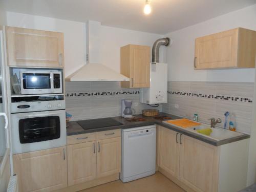 une cuisine avec des appareils électroménagers blancs et des armoires en bois dans l'établissement appartement frejus plage, à Fréjus