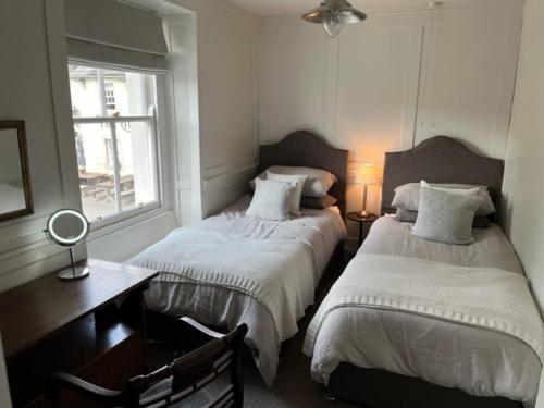 1 dormitorio con 2 camas, escritorio y ventana en Old Cross Cottage, en Penrith