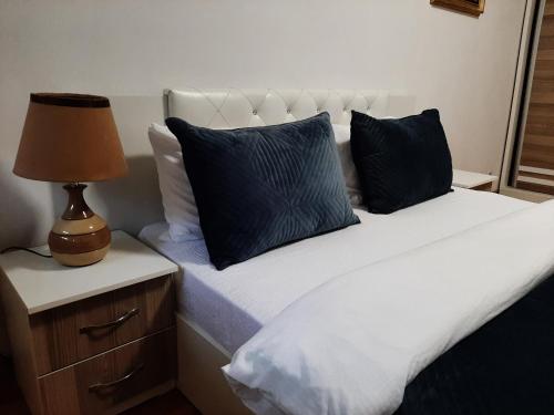 - un lit avec deux oreillers et une lampe sur une table de nuit dans l'établissement Prishtina Central Apartment, à Pristina
