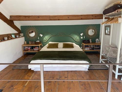 a bedroom with a bed with a green headboard and two mirrors at Appartement dans Mas Provencal in Grans