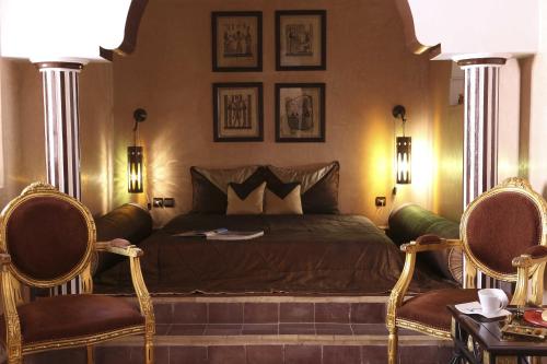 una camera da letto con un letto con due sedie di Riad Mille Et Une Nuits a Marrakech