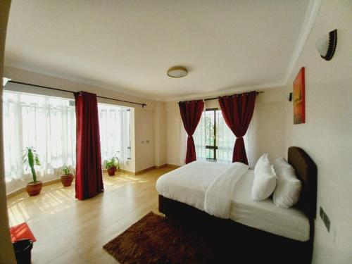 a bedroom with a large bed with red curtains at FH apartments opposite culture mambo in Nakuru