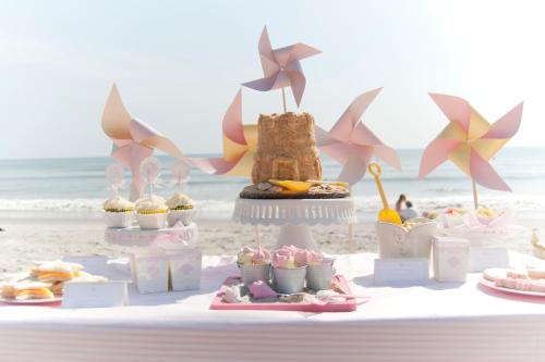 a table with cupcakes and a cake on the beach at Most Requested 16 Br Oceanfront Home in Holden Beach in Holden Beach