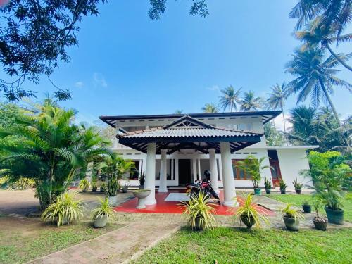 a white house with palm trees in front of it at Villa bodhi Ahangama, Home stay in Ahangama