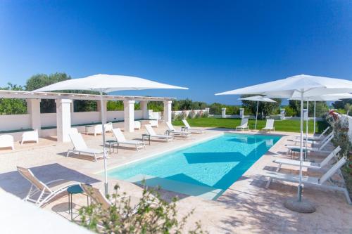 a swimming pool with chairs and umbrellas and a pool at Tenuta Amostuni-Country House in Ostuni