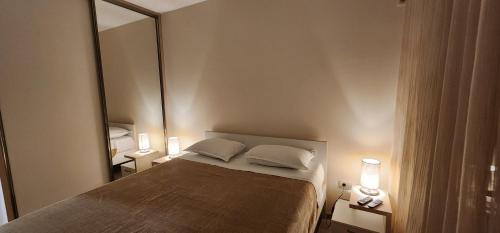 a bedroom with a bed with two lamps and a mirror at City apartment in Podgorica