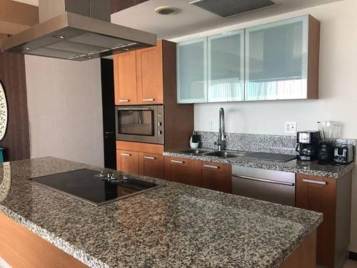 a kitchen with a granite counter top and wooden cabinets at Departamento de Lujo Vista al mar Piso 15 in Mazatlán