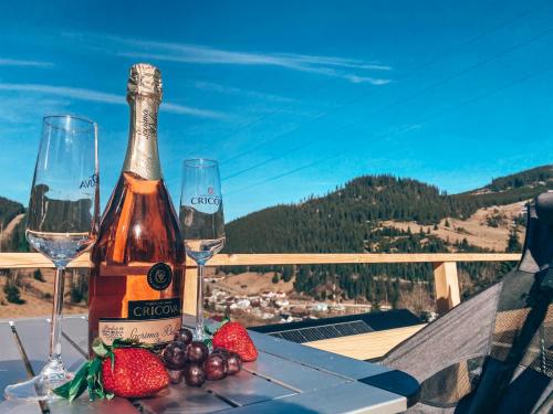 a bottle of wine and two glasses and strawberries on a table at Cucu Zen Dome Cabana Cazare Bucovina 