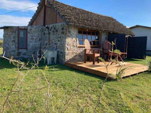 a small stone cottage with a wooden deck in front of it at Quincho Nativo in Tacuarembó