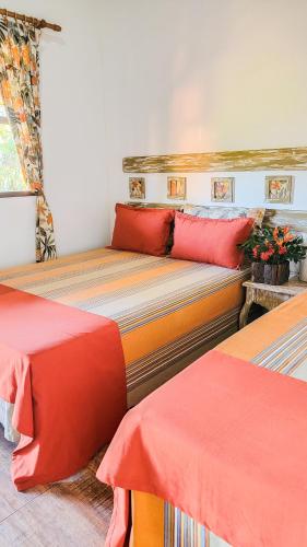 a bedroom with two beds with red and orange pillows at Mirante de Lençóis in Lençóis