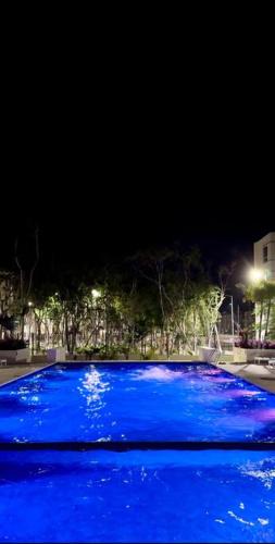 a blue swimming pool at night with lights at Departamento eco-chic a 10 min del centro in Tulum