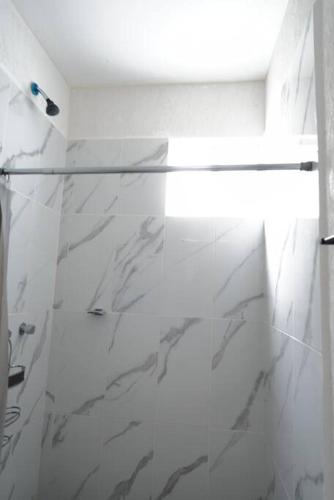 a white bathroom with a glass shower door at Departamento eco-chic a 10 min del centro in Tulum