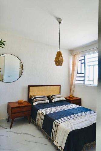a bedroom with a large bed and a mirror at Departamento eco-chic a 10 min del centro in Tulum