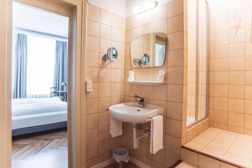 a bathroom with a sink and a mirror and a bed at Auberge d'Ajoie in Porrentruy