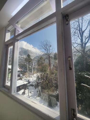 una ventana abierta con vistas a una montaña nevada en Samye hotel, en Lachung