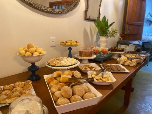a table filled with different types of bread and pastries at Pousada Mãe Natureza in Pirenópolis