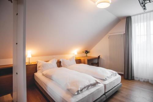 a bedroom with a bed with white sheets and pillows at Auberge d'Ajoie in Porrentruy
