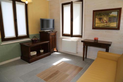 a living room with a tv and a couch and windows at Borgo Tiedoli in Borgo Val di Taro