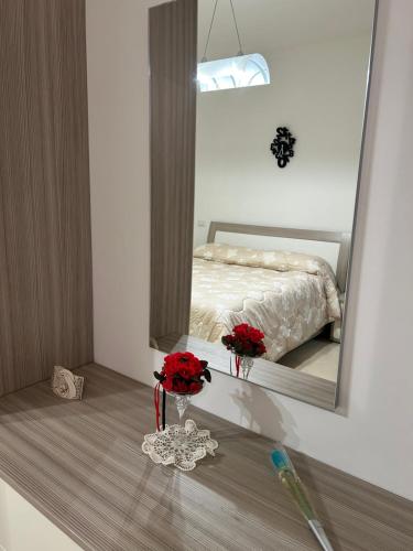 ein Schlafzimmer mit einem Bett mit roten Rosen im Spiegel in der Unterkunft Appartamento A Casa Nostra in Rivotorto