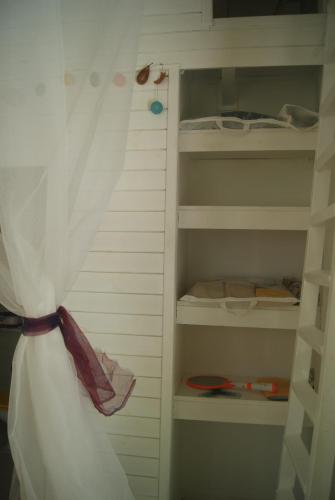 un placard avec des étagères blanches et un rideau dans l'établissement Kaz à Skanky, au Gosier