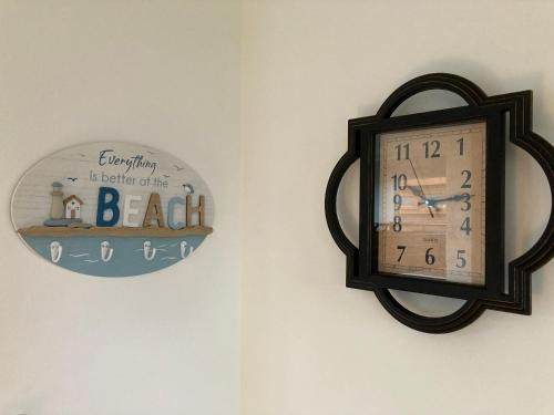 a clock hanging on a wall with a beach sign at J16 Mablethorpe Pet Friendly Chalet in Mablethorpe