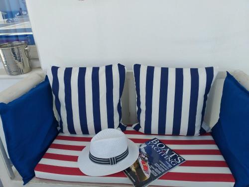 a hat and a book on a striped couch at Yacht Marine Maison in Naxos Chora
