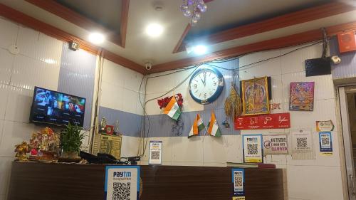 a room with a clock on the wall and a tv at Hotel Air View in kolkata