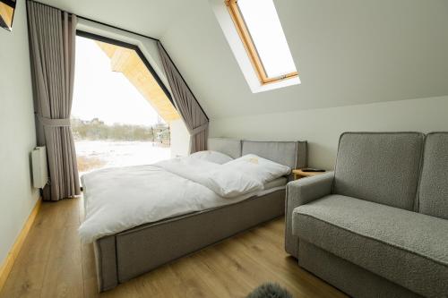 1 dormitorio con cama, sofá y ventana en Hreśkowa Osada - Domki w Górach en Szaflary