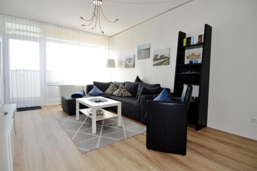 ein Wohnzimmer mit einem schwarzen Sofa und einem Tisch in der Unterkunft Ferienpark Hs N Etage 8 Whg 2 in Heiligenhafen