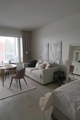 a white living room with a couch and a table at Ihana yksiö Kangasalan Harjunsalossa in Kangasala