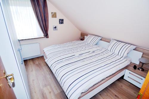 ein kleines Schlafzimmer mit einem Bett mit gestreifter Bettwäsche in der Unterkunft Sandkamp 7 Wohnung 3 in Heiligenhafen