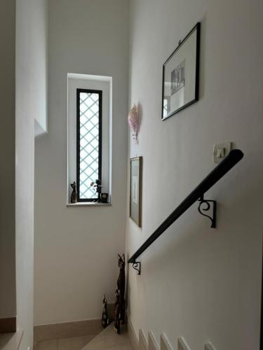a staircase with a window and a black rail at Lilly & Gisa casa vacanze in Pedara