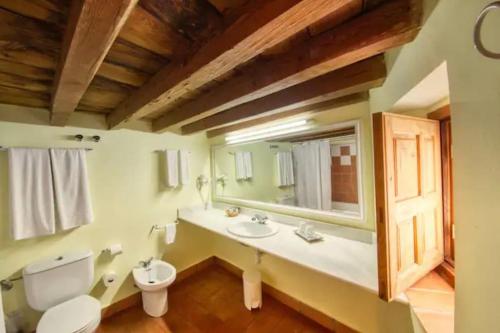 baño con lavabo y aseo y ventana en Casa Bermeja, en Valdeverdeja