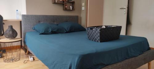 Una cama con sábanas azules y una cesta. en Location chambre chez particulier pour 24h du mans et le mans classique, en Mulsanne