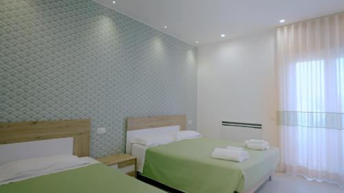 een slaapkamer met 2 bedden en groene lakens bij Villa Zefiro Suites e Events in Battipaglia