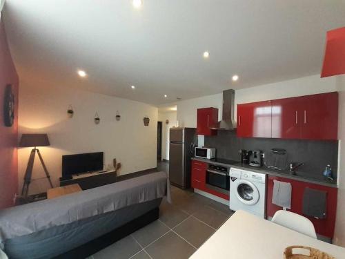 - une cuisine avec des placards rouges et un canapé dans la chambre dans l'établissement Proche Gare et Centre Ville, à Narbonne