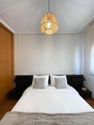 een slaapkamer met een groot wit bed en een kroonluchter bij Apartamento Nuskis in Porriño