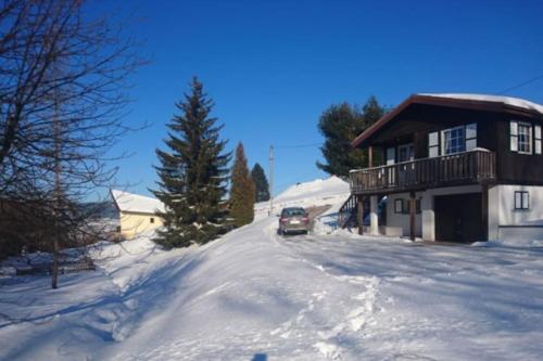 a car driving down a snow covered road next to a house at Le P'tit Caribou, près des pistes in Gérardmer