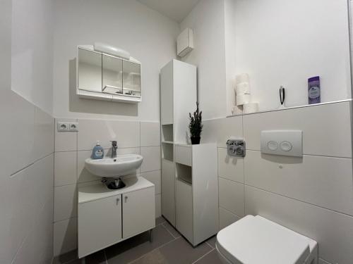 a white bathroom with a sink and a toilet at Simplex Apartments Am Europaplatz in Karlsruhe