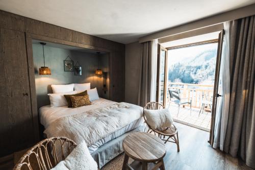 een slaapkamer met een bed en een balkon met uitzicht bij Hôtel de la Roche in Beaufort