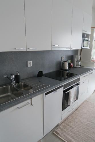 a kitchen with white cabinets and a sink at Ihana yksiö Kangasalan Harjunsalossa in Kangasala