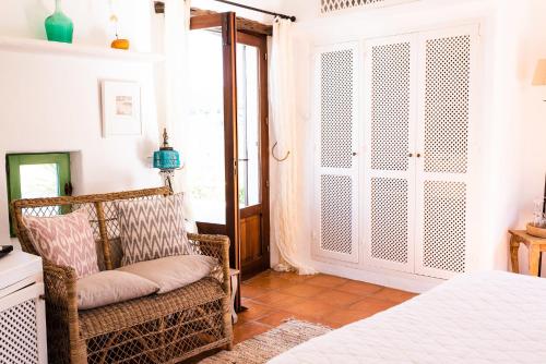 a bedroom with a bed and a chair and a window at ES CUCONS RURAL HOTEL in San Antonio