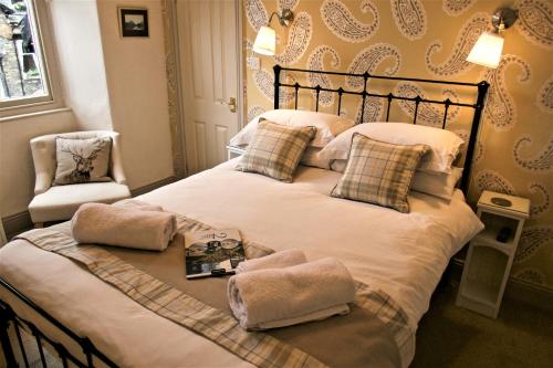 a bedroom with a large white bed with a chair at 2 Cambridge Villas B & B in Ambleside