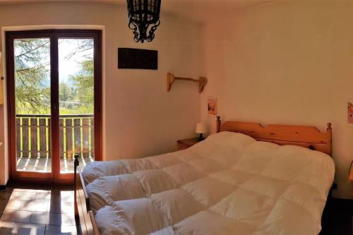 a bedroom with a white bed and a balcony at Appartamento Valdobbia in Gressoney-Saint-Jean