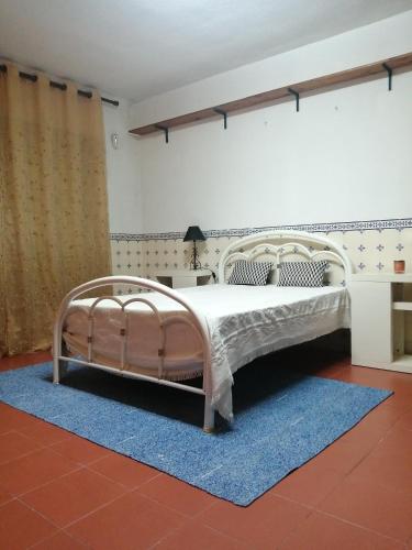 a bedroom with a white bed with a blue rug at Good Sleep in Santarém