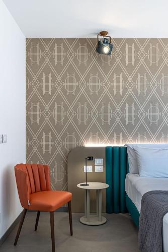 a bedroom with a bed and a chair and a table at DIVA HOTEL LIGNANO - Adults Only in Lignano Sabbiadoro
