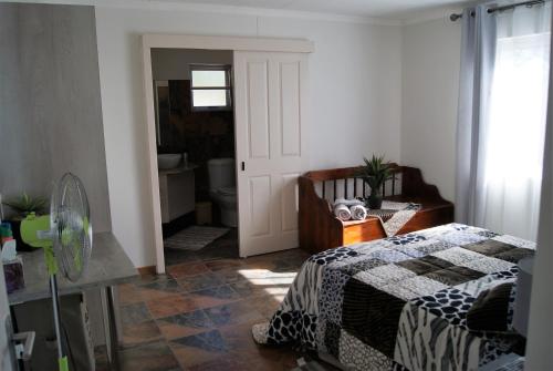 a bedroom with a bed and a chair and a bathroom at Orpheus Inn in Kaneb Pos