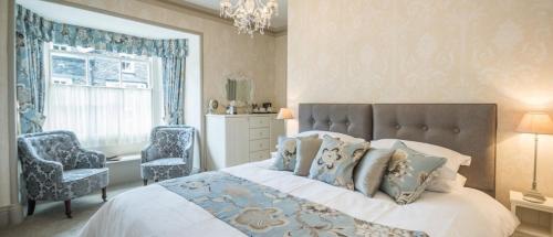a bedroom with a bed and a chair and a window at 2 Cambridge Villas B & B in Ambleside